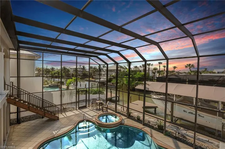 Pool at dusk with an in ground hot tub, enclosure, and a patio