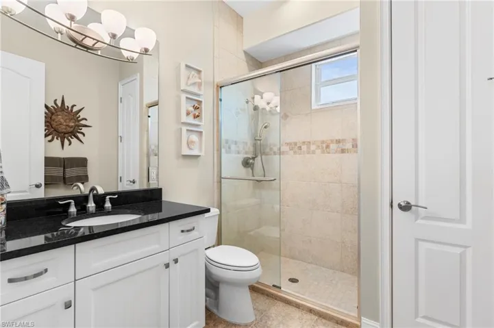 Bathroom with tile patterned floors, toilet, a shower with shower door, a chandelier, and vanity