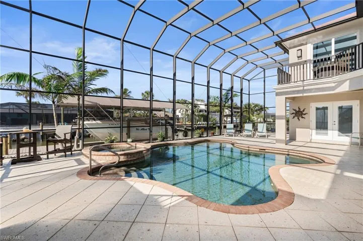 View of pool with a lanai, a patio area, french doors, and an in ground hot tub