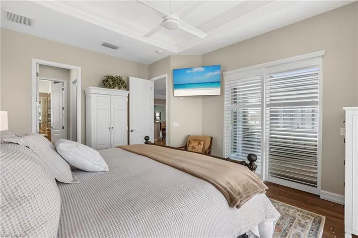 Bedroom featuring a tray ceiling, dark wood-type flooring, ceiling fan, and access to outside