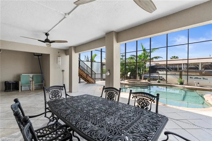 Poolside terrace dining area with ceiling fan and a textured ceiling