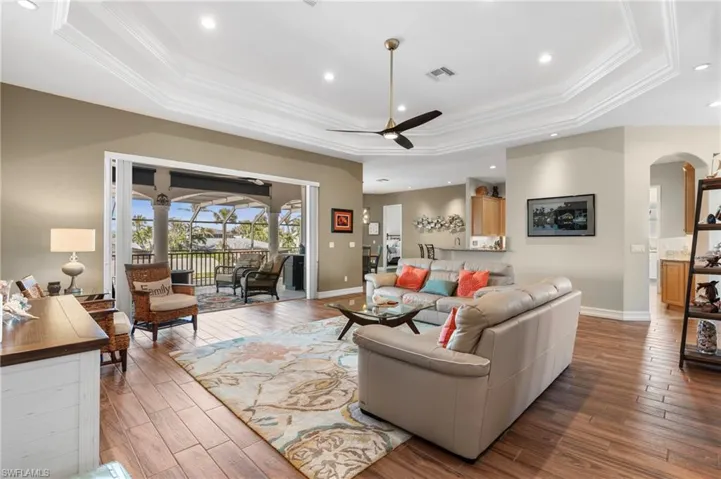 Living room with crown molding, hardwood / wood-style floors, a tray ceiling, and ceiling fan