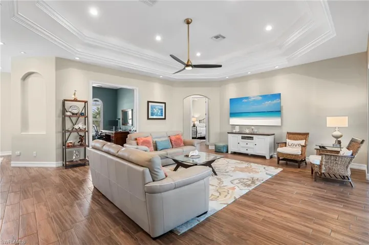 Living room featuring ornamental molding, light hardwood / wood-style flooring, and a tray ceiling