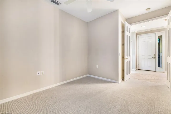 Den with French doors and neutral carpeting
