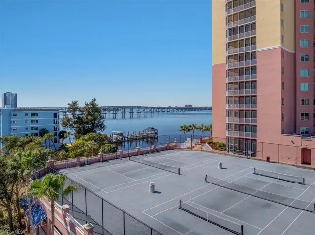 View of tennis court with a water view