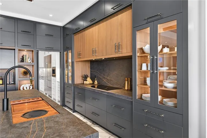 Kitchen featuring two tone cabinets, backsplash, modern cabinets, glass fronted cabinets, and black electric cooktop