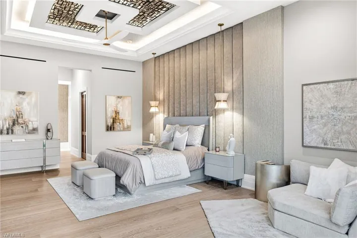 Bedroom with an accent wall, wood finished floors, and a tray ceiling
