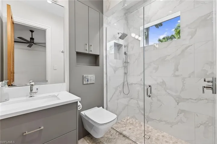 Bathroom with vanity, a marble finish shower, and ceiling fan
