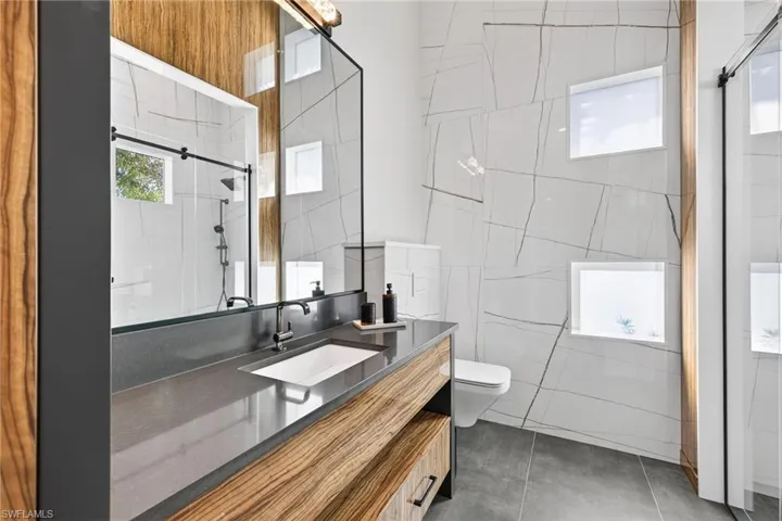Bathroom with vanity, tiled shower, and tile walls