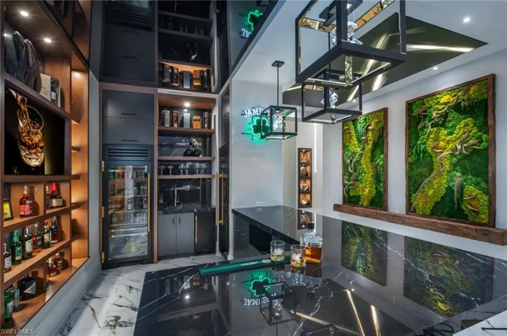 Indoor bar with light marble finish flooring, beverage cooler, and decorative light fixtures