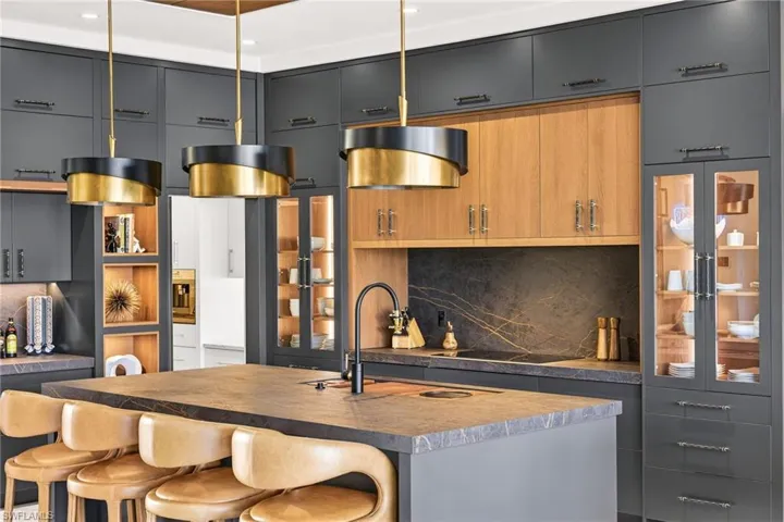 Kitchen featuring two tone cabinets, decorative backsplash, a kitchen bar, and an island with sink