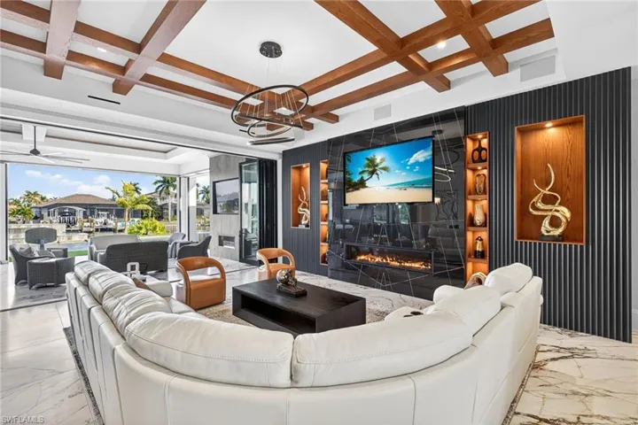 Living room with coffered ceiling, marble tiled flooring, recessed lighting, a high end fireplace, and a ceiling fan