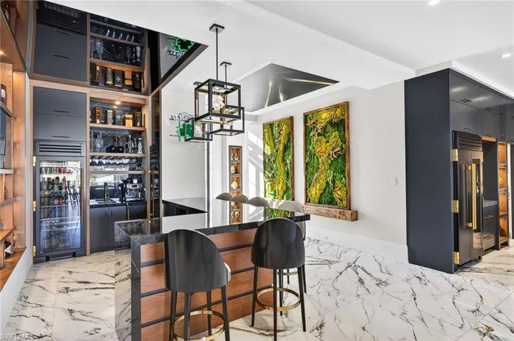Indoor wet bar featuring pendant lighting, high end refrigerator, dark cabinets, and modern cabinets