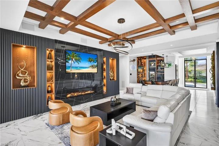 Living area with coffered ceiling, recessed lighting, marble finish floors, a fireplace, and an accent wall