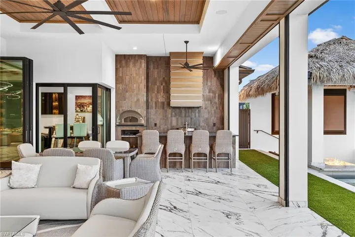 View of patio / terrace featuring ceiling fan, an outdoor bar and dining area, and a large fireplace