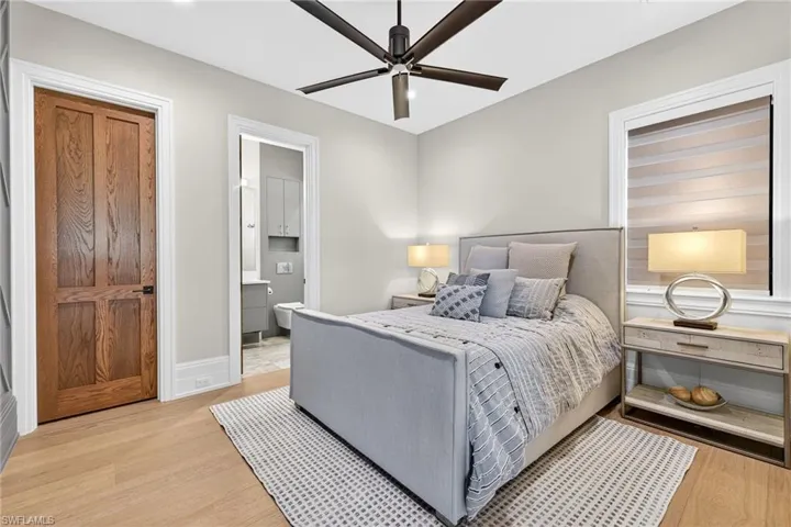 Bedroom featuring light wood-style flooring, ceiling fan, and ensuite bath