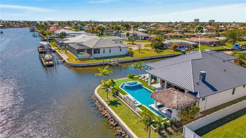 Aerial view of residential area featuring a nearby body of water and a pool area