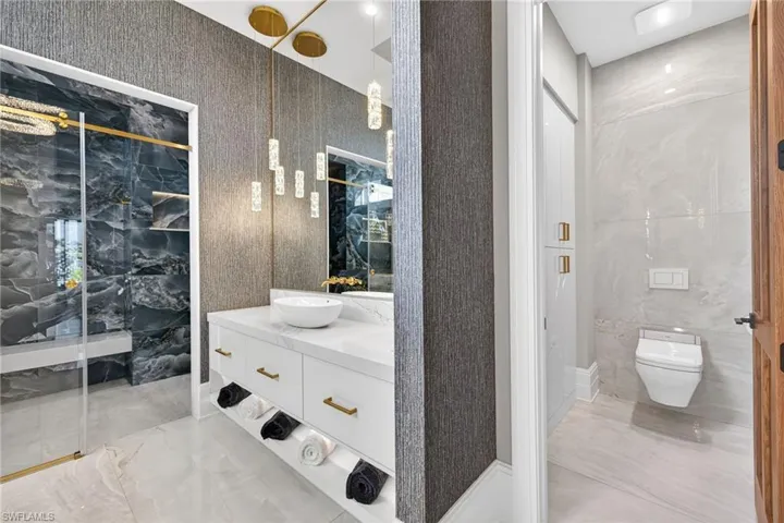 Full bath featuring vanity, light marble finish flooring, and a marble finish shower