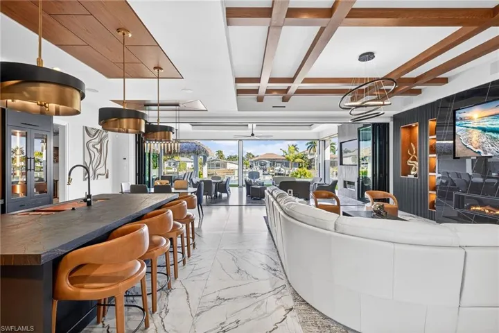 Living area featuring coffered ceiling, light marble finish flooring, and ceiling fan