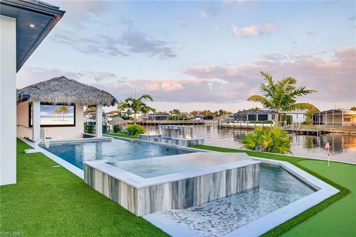 View of pool with a water view, an infinity pool, an area to practice putting, and patio surround