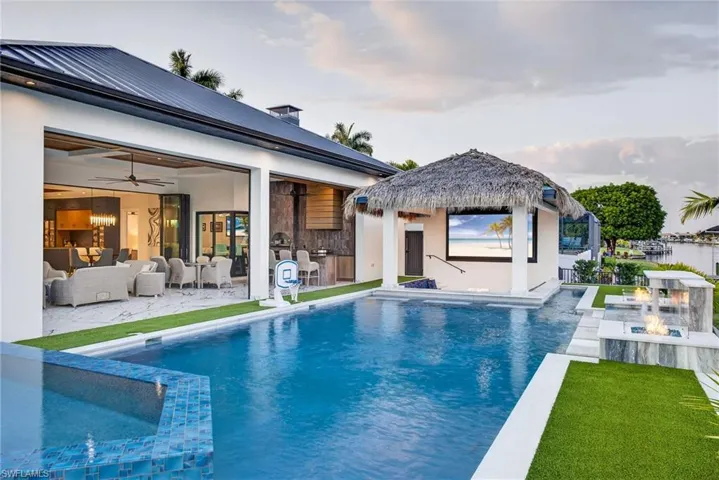 Rear view of house featuring a pool with connected hot tub, stucco siding, an outdoor hangout area, a patio, and ceiling fan