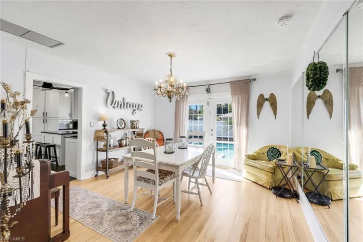 Dining area featuring suspended lighting, light wood-type flooring, and french doors to swimming pool and courtyard