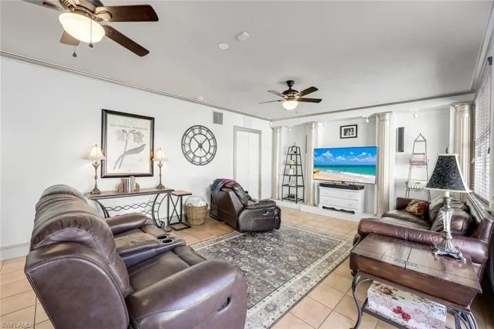 Living room with crown molding, a ceiling fan, and light tile patterned flooring