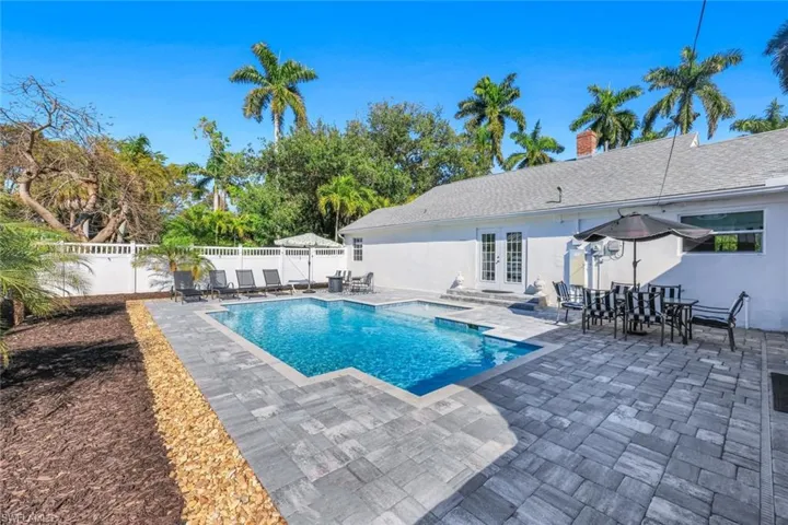 View of pool with french doors, outdoor dining area, patio surround, and a fenced backyard