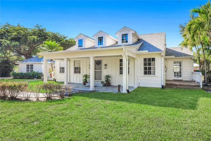 View of front of home with board and batten siding, a front lawn, a porch, and roof with shingles