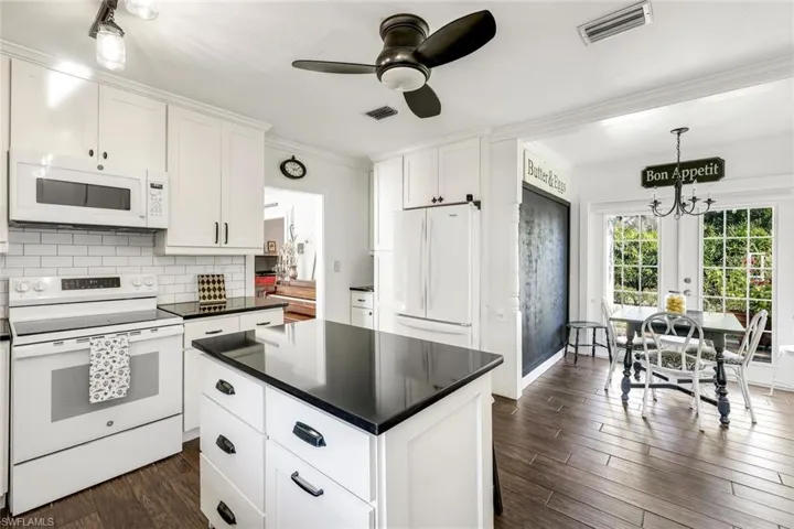 Kitchen with white appliances, white cabinets, ornamental molding, dark wood-type flooring, and pendant lighting