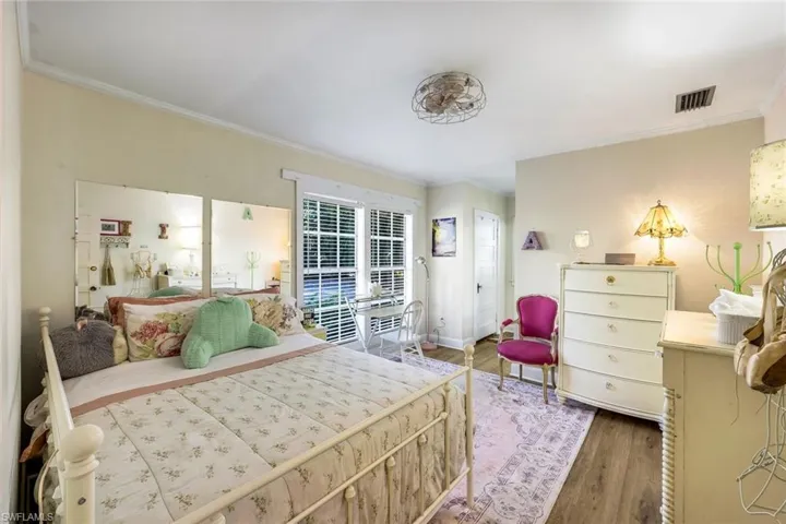 Bedroom with wood finished floors and crown molding