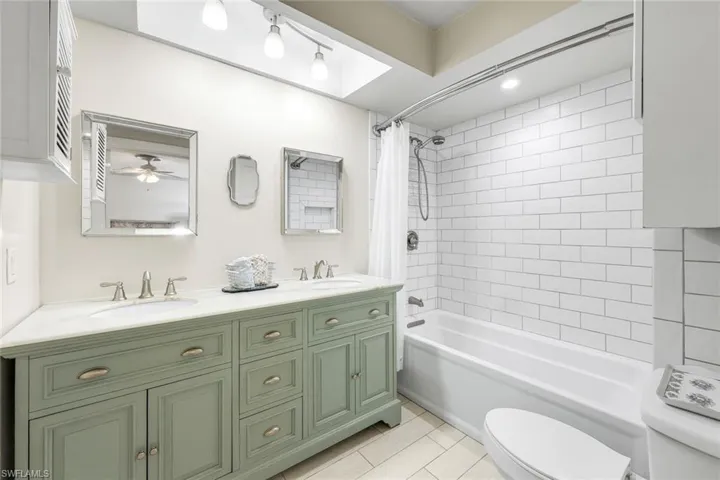 Bathroom with double vanity, shower / bath combo, and light tile patterned floors
