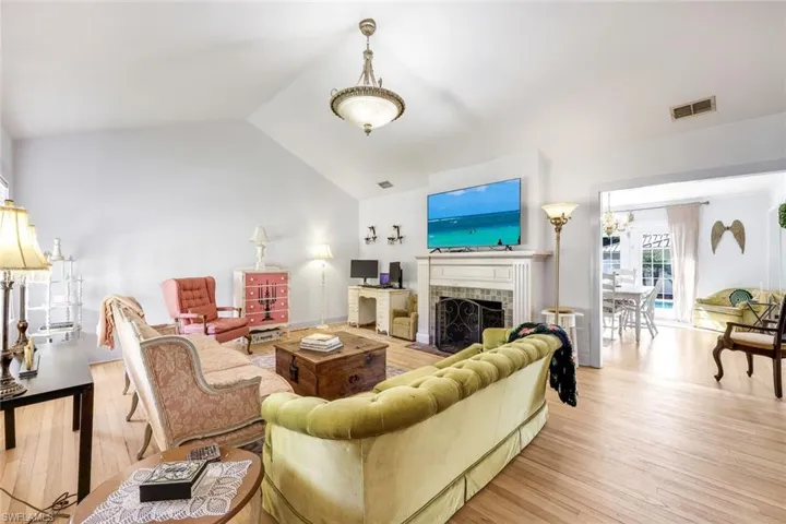 Living area featuring hardwood floors, a brick fireplace, and a high ceiling