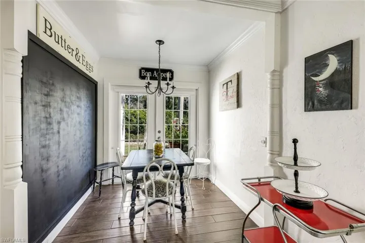 Dining room with crown molding, dark wood finished floors, a textured wall, french doors, and hanging lights