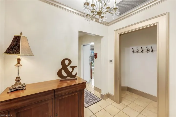 Hallway with light tile patterned floors, a chandelier, and crown molding