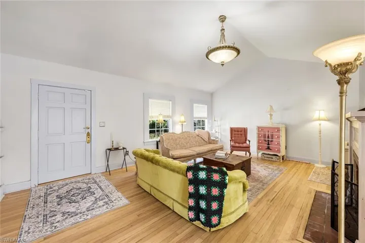 Living area featuring a brick fireplace, lofted ceiling, and light wood flooring