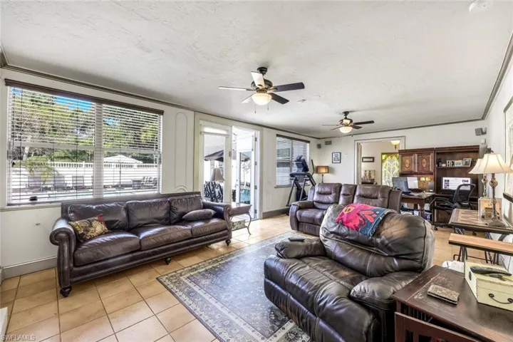 Living area featuring light tile patterned floors, a textured ceiling, and ceiling fan
