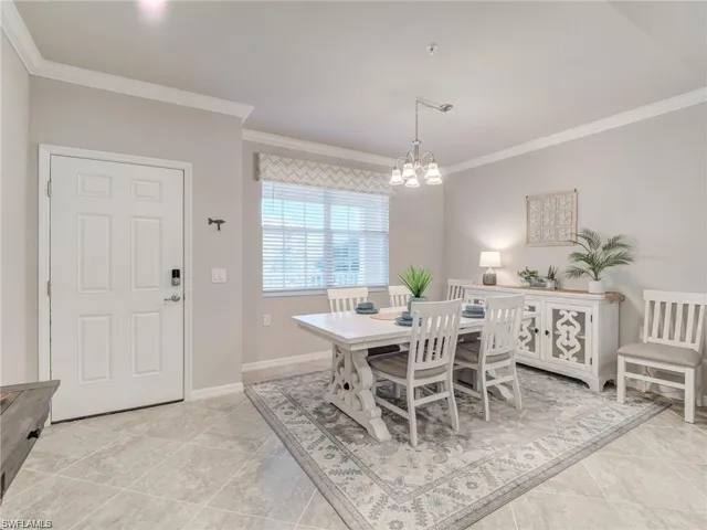 Tiled dining room with a notable chandelier and crown molding