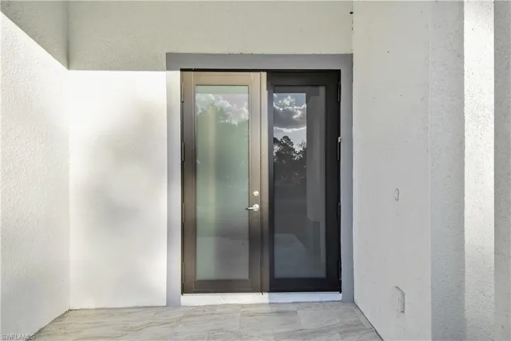 View of exterior entry featuring stucco siding and french doors