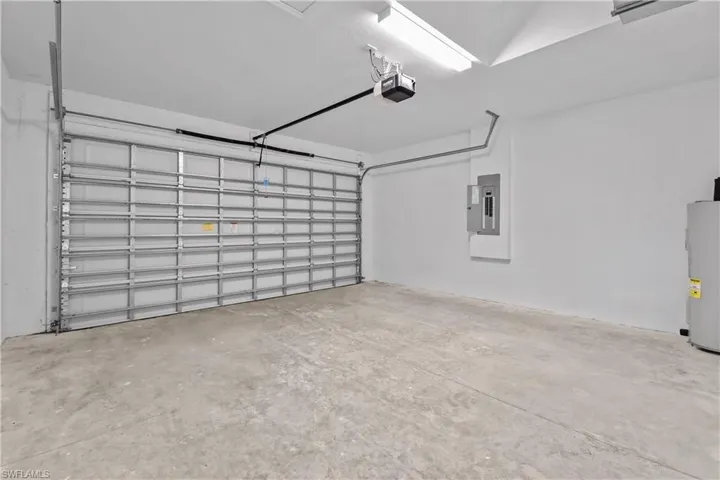 Garage with electric panel, electric water heater, and a garage door opener