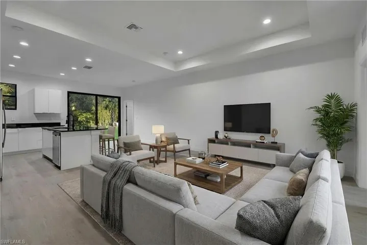 Living room with recessed lighting, light wood-style flooring, and a tray ceiling