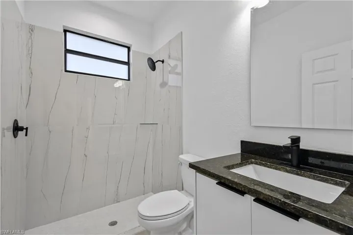 Bathroom with vanity, a marble finish shower, and a textured wall