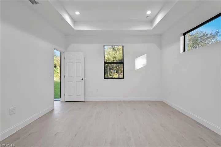 Spare room with light wood-style floors, a tray ceiling, and recessed lighting