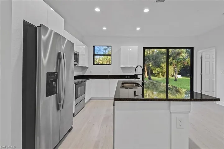 Kitchen with stainless steel appliances, dark stone counters, recessed lighting, modern cabinets, and white cabinetry