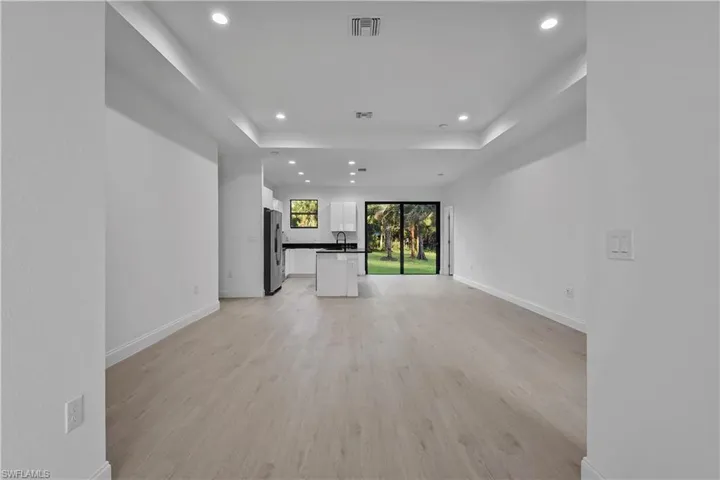 Unfurnished living room featuring light wood-style flooring, recessed lighting, and a tray ceiling