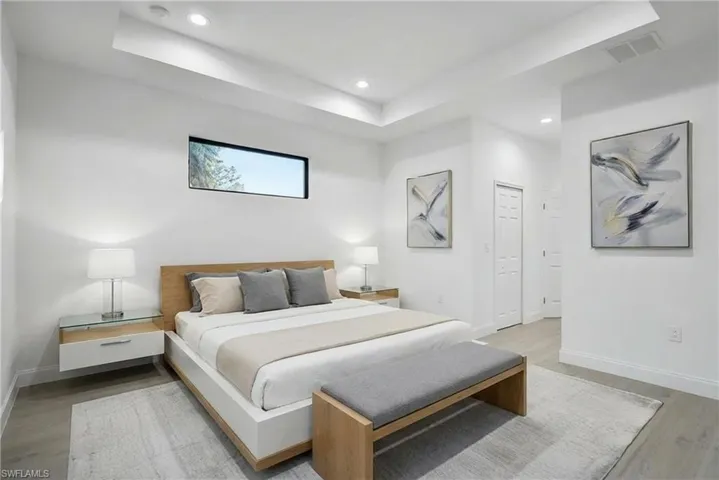 Bedroom featuring a raised ceiling, light wood finished floors, and recessed lighting
