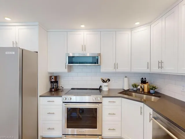 Kitchen with stainless steel appliances, tasteful backsplash, sink, and white cabinets