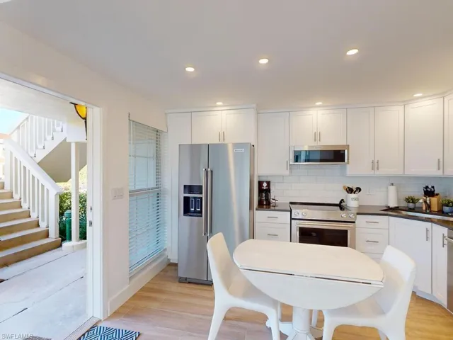 Kitchen featuring white cabinets, stainless steel appliances, light hardwood / wood-style floors, and tasteful backsplash