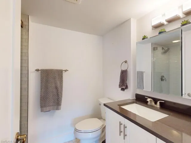 Bathroom featuring toilet, vanity, and a tile shower
