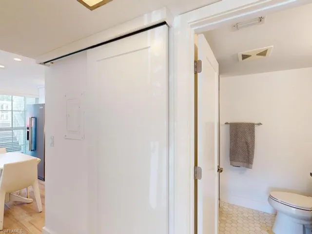 Bathroom with hardwood / wood-style floors, electric panel, toilet, and walk in shower
